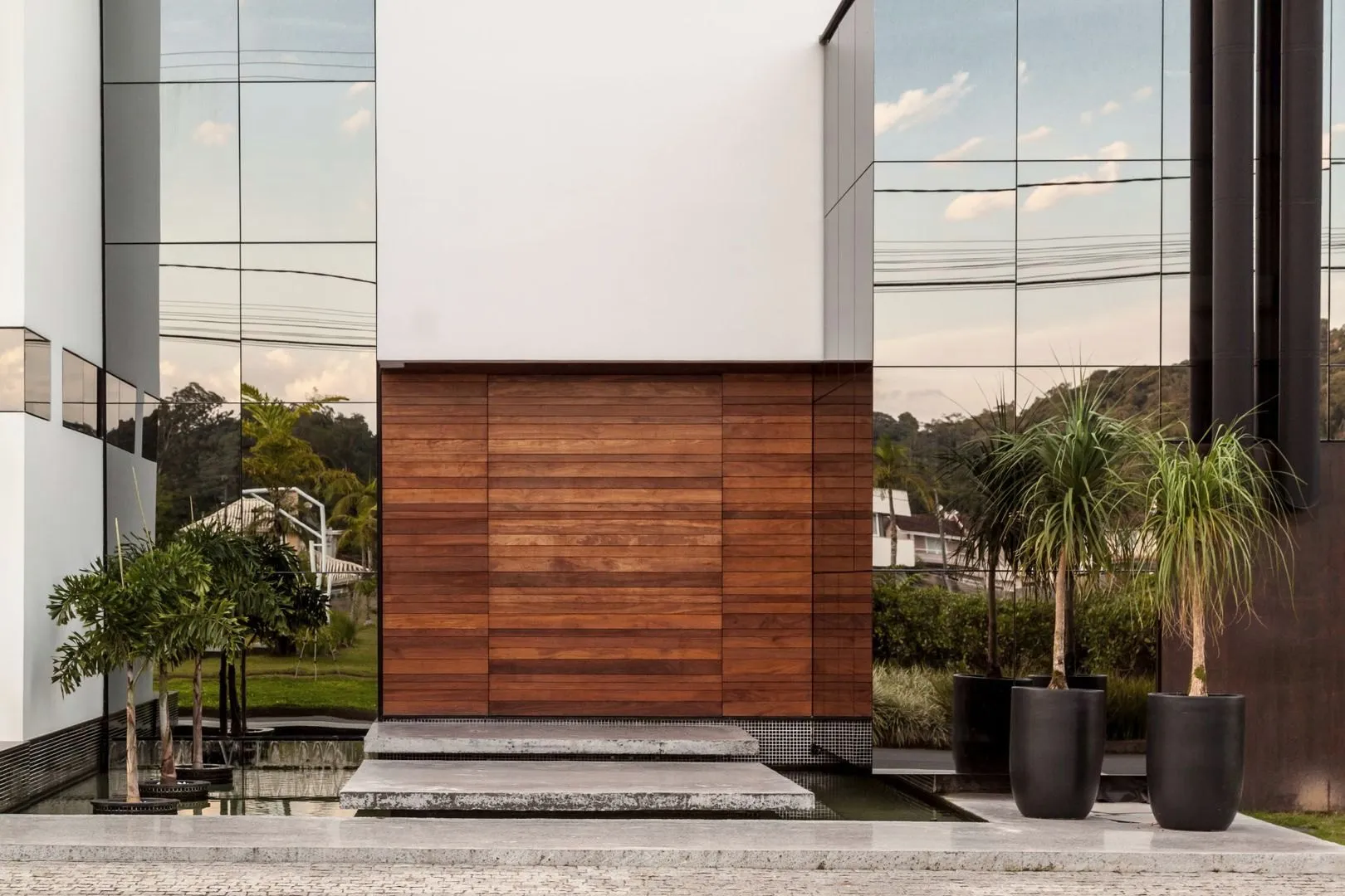 Fachada de casa com porta de madeira, vidro e vasos